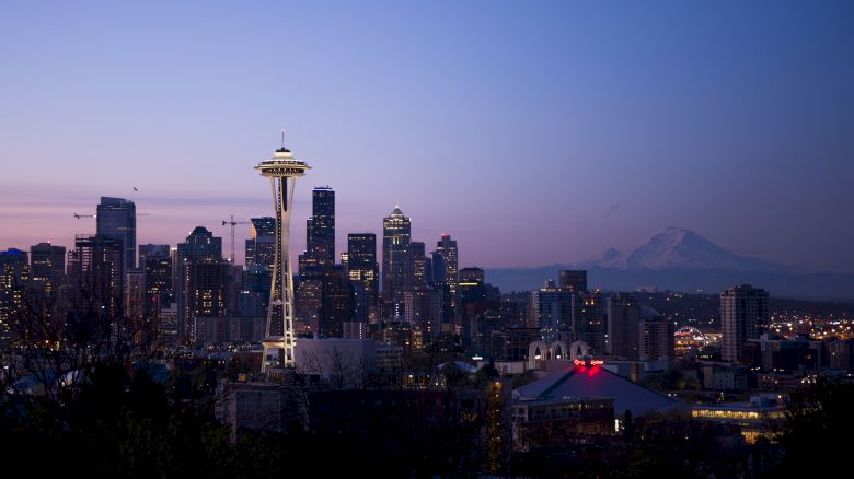 This image shows the Seattle skyline at dusk, featuring the Space Needle prominently, with Mount Rainier in the background.